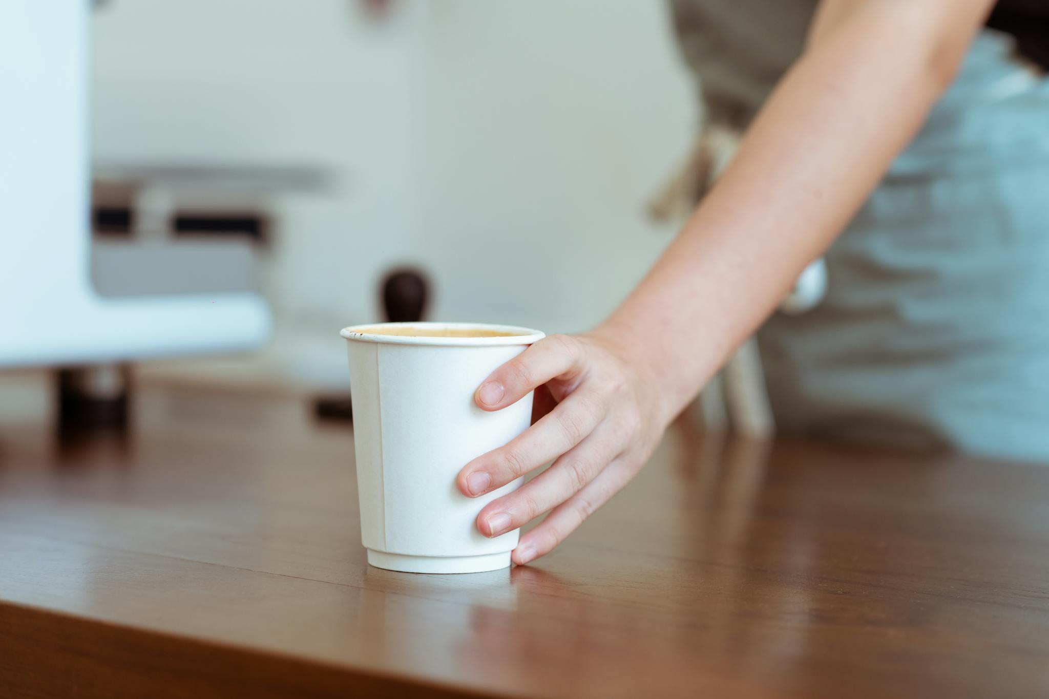 Crop barista serving coffee in paper cup