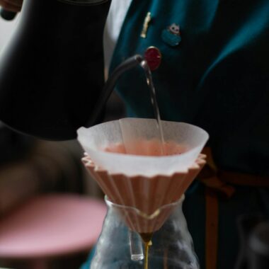 Crop faceless barista pouring hot water into chemex