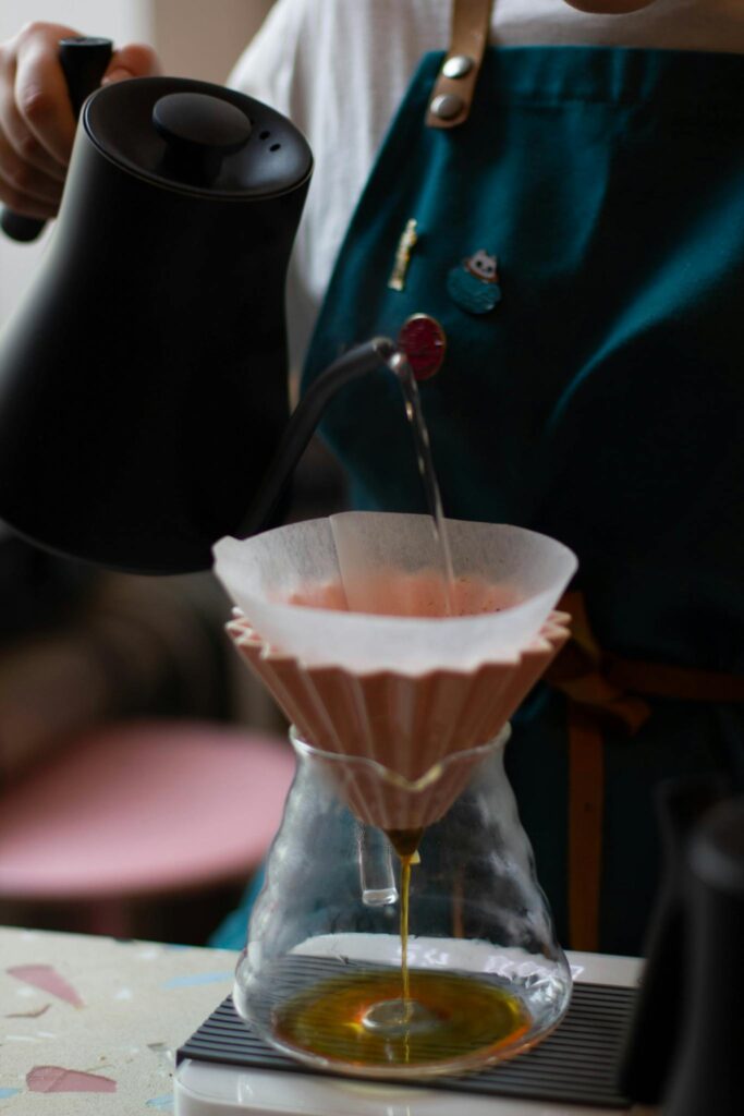 Crop faceless barista pouring hot water into chemex